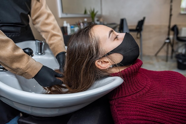 In the new prestigious salon a master in special gloves\
prepares a client to wash her head in a special chair during an\
epidemic hairdressing concept beauty salon concept