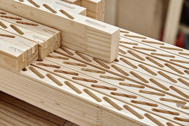 Новые обработанные деревянные брусья с линиями пазов для установки тонких досок лежат на верстаке в мастерской