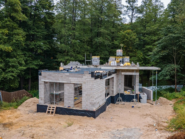 Фото Новый жилой дом в строительстве с бетонными блоками и строительными материалами в лесистой местности