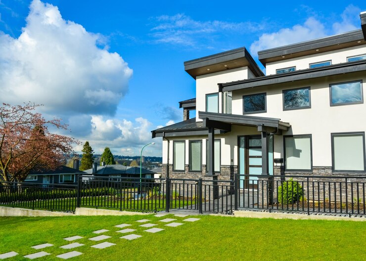 New residential house with concrete tile pathway over front lawn and metal fence in front