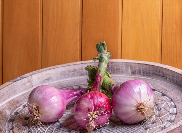 New season purple onions on wooden tray.