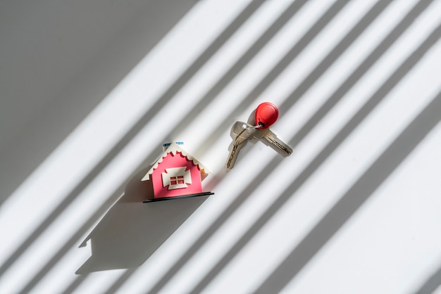 A new small toy house with pair of keys concept of new apartment purchase flat lay