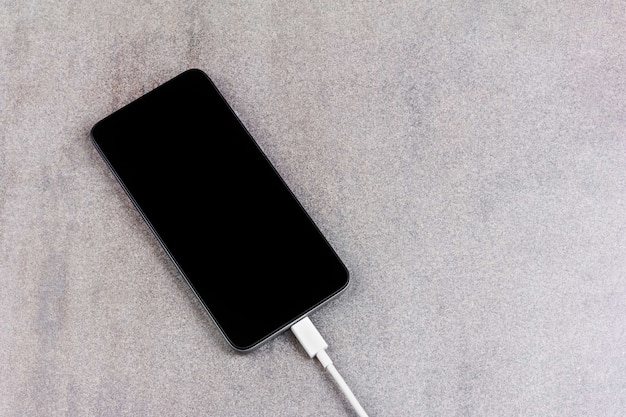 New smartphone with a black screen with a white wire from the charger