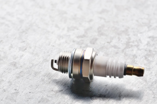 New spark plug for internal combustion engine on metal background. Space for text