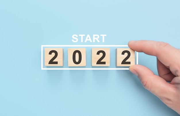 Новая концепция старта 2022 года Загрузка нового 2022 года с рукой, помещающей деревянный куб в индикатор выполнения