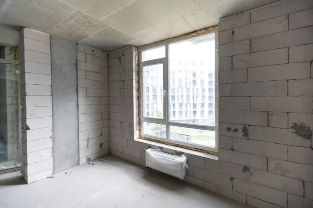 장식이 없는 맨 벽돌 벽으로 마감되지 않은 새로운 아파트 방입니다.