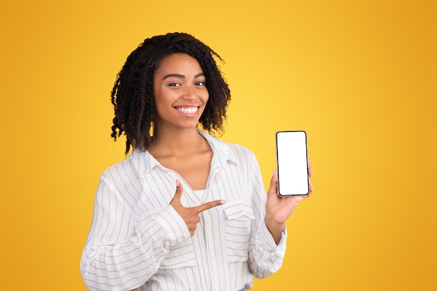 New useful application happy black girl showing cell phone with white blank screen pointing at it