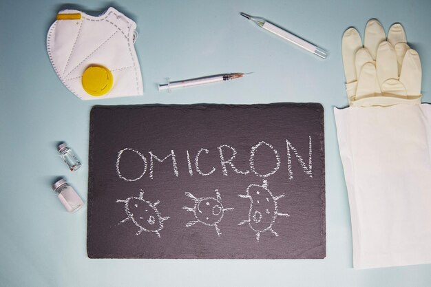 Covid19 Omicron B11529 텍스트의 새로운 변종 얼굴 마스크 백신 장갑 주사기 및 온도계 Omicron 변종 코로나바이러스 분필 칠판에 텍스트