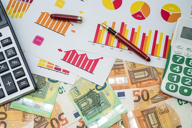 new various graphs pen calculator arranged on new euro banknotes. Business concept