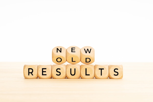 New vs old results symbol in wooden blocks on table. White background. Copy space