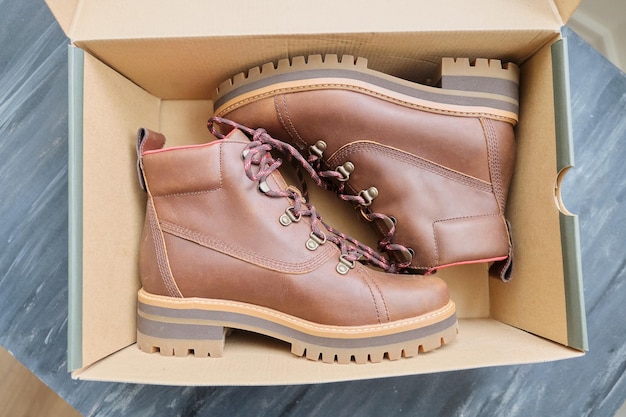 New womens leather brown waterproof hiking winter autumn boots in a box, trendy footwear for winter. Unpacking boots, shopping online from home, shoe fashion store