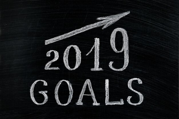 New Year 2019 goals with a rising arrow text chalk on a blackboard