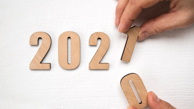 손으로 나무 테이블에 나무 숫자 2021을 넣어 새 해 2021 개념