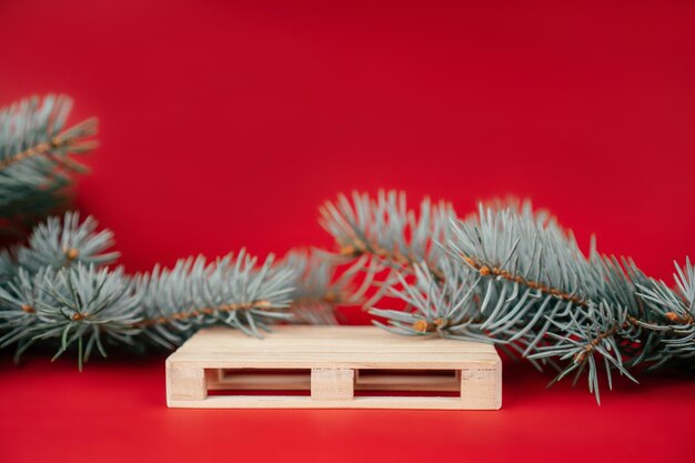 New year 2022. wooden pallet on red surface with christmas tree branches. podium, pedestal or stage. merry christmas