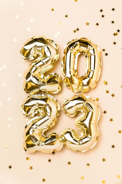 New year 2023 balloon celebration card gold foil helium balloon\
number 2023 party decoration gold confetti stars on beige\
background flat lay merry christmas happy holidays concept