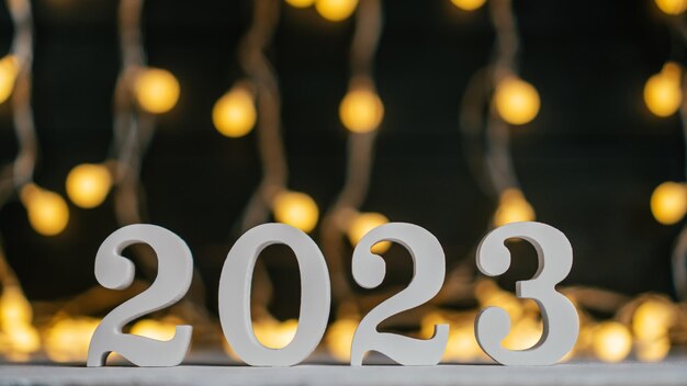 새해 2023 흰색 나무 숫자 2023은 화환 전구 복사 공간에 대 한 서