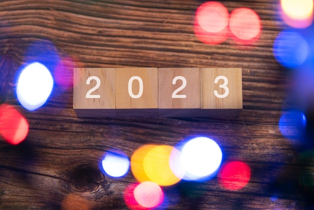 New Year 2023 on wood block with Christmas light flat lay