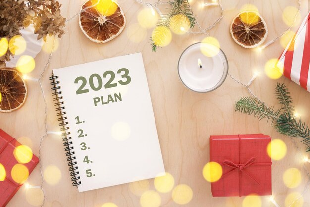 New Year Aims 2023 To Do List writing Writing in Empty Notebook at Wood Table with Christmas Decor Top view Creating Goal List Resolutions New Life Start Up Beginning Concept Business ideas