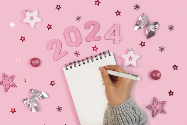 Photo new year aims 2024 to do list empty notebook at the desk with holiday decoration top view female hand creating plan resolution new life start up beginning concept business idea goals action