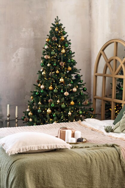 New year background. Cozy Christmas loft room interior. Lighting, gifts, candles and indoor hot lighting, garlands, Christmas trees with gifts. Soft selective focus.