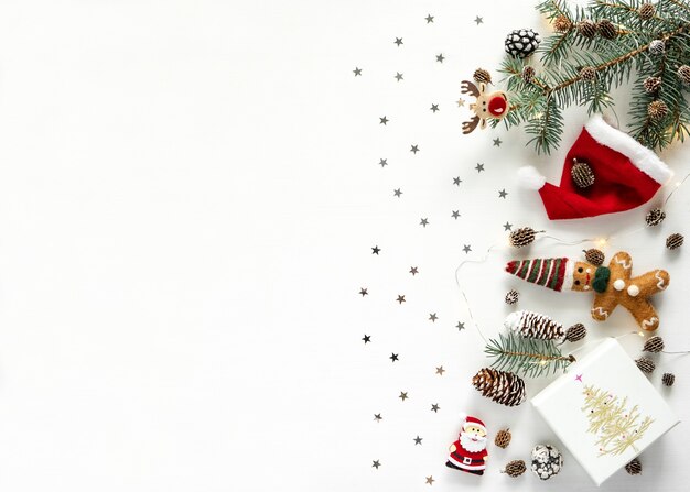 New Year background. Pine cones, shining stars, red hat and lanterns on white background with copy space, flat lay