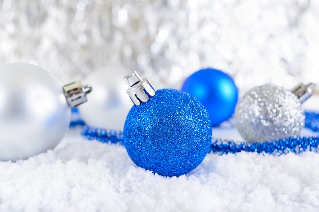 New Year banner with blue, silver and white Christmas balls in snow on abstract winter background. Xmas decoration. Merry christmas.