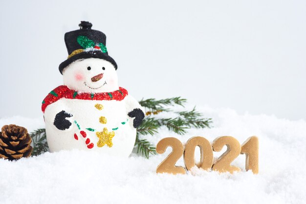 New Year card. Christmas toy cute snowman, numbers 2021, fir branches pine cone in the snow. copy space.