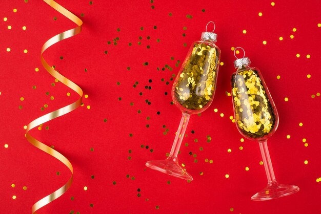 New year celebration concept. Top above overhead view photo of champagne glasses with golden confetti inside isolated on red background with confetti