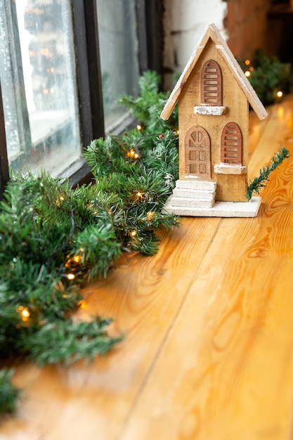 New Year and Christmas background or greeting card. Toy wooden house on windowsill. Place for text.