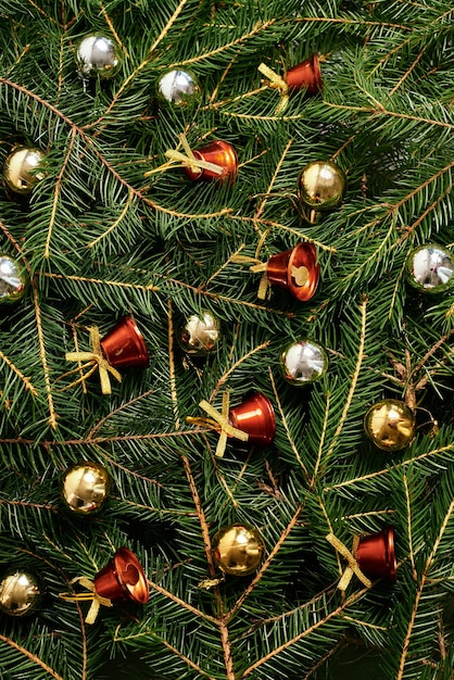 Foto sfondo di natale di capodanno con rami di abete, albero di natale, giocattoli, palline d'oro, campane rosse