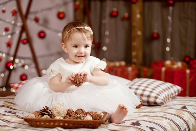 Концепция празднования нового года и Рождества. Хорошенькая девочка в белом платье, играть и быть счастливым о елки и огни. Зимние каникулы.
