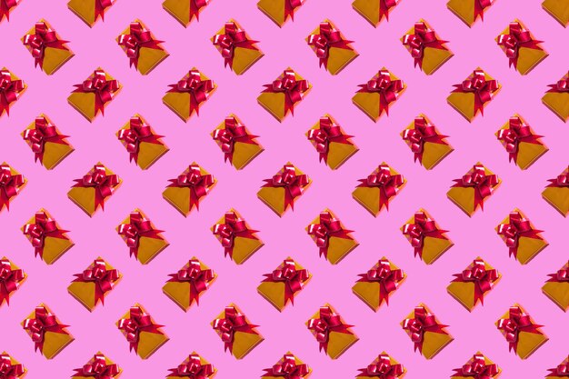 Photo new year christmas composition. gold gift with a red bow on a pink background. top view copy space new year 2022 christmas.pattern