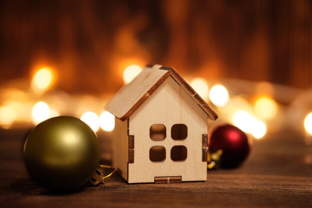 New year and christmas concept on wooden background with garlands and toy house