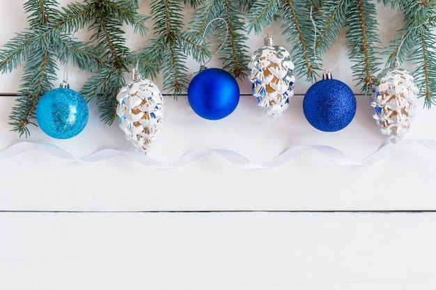 Decorazione per cornice di capodanno e natale con rami di abete verde e palline tradizionali lucide blu e argento. biglietti d'invito di auguri su sfondo bianco.