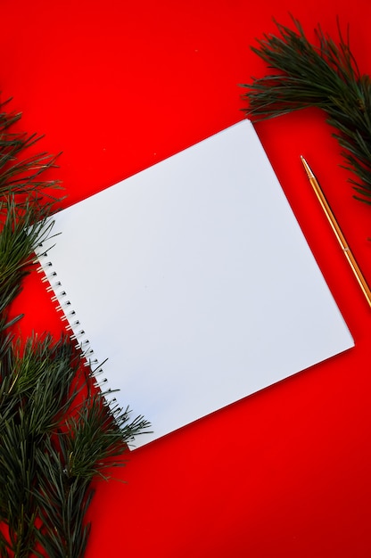 New Year and Christmas template A white notebook and a golden pen lie on a red background
