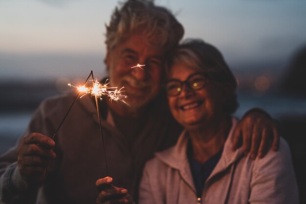 Photo new year. close up of seniors celebrating the new year together at the beach with sparklers lights