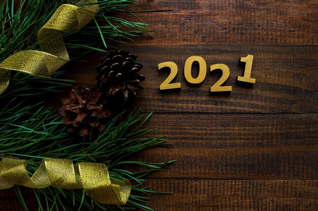 Composizione di capodanno con numeri d'oro 2021 con rami di pino, pigne e nastri dorati