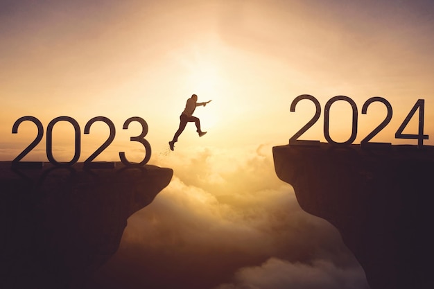 New year concept Businessman jumping gap on the cliff from number 2023 to number 2024