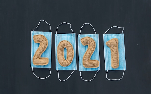 Il nuovo anno nel contesto del coronavirus ha lavorato a maglia i numeri 2021 sulla mascherina medica sulla lavagna