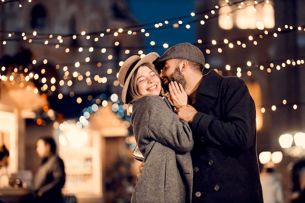 New Year couple kissing on the street on New Year's eve A young couple in love standing on the street on New Year's eve hugging and kissing