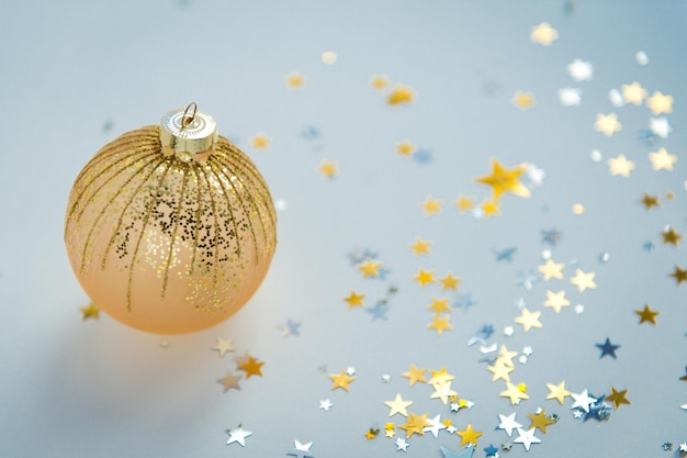 New year decor single golden ball with confetti on color background