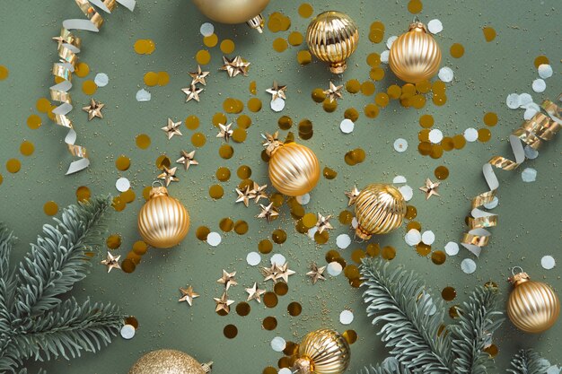 Photo new year decorations golden color with confetti and fir branches on color background