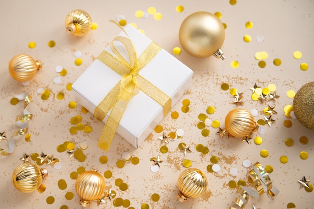 Decorazioni di capodanno colore dorato con coriandoli e confezione regalo su sfondo colore beige