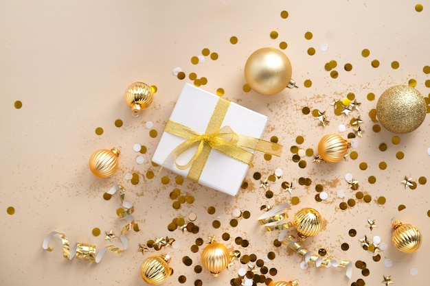 New year decorations golden color with confetti and gift box on\
beige color background