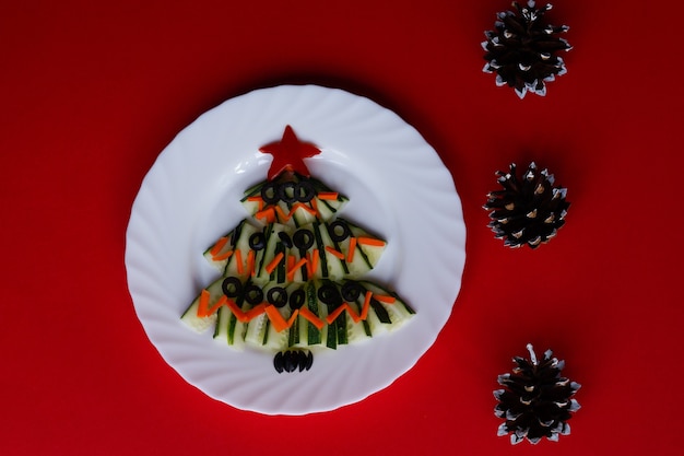 New Year food Christmas tree made of cucumber salad on a red background with cones