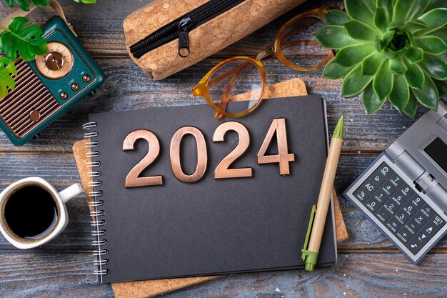 Foto obiettivi per il nuovo anno 2024 sulla scrivania elenco degli obiettivi del 2024 con quaderno pianta di tazze da caffè su tavolo di legno risoluzioni piano obiettivi lista di controllo azione idea concetto risoluzioni per il nuovo anno 2024 spazio per la copia