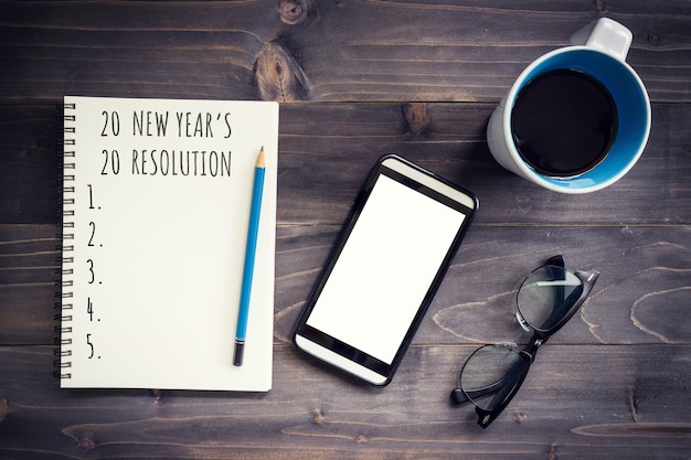 New Year goals, resolution or action plan 2020 . Office wood table with blank notepad, pencil, glasses, phone and cup of coffee.