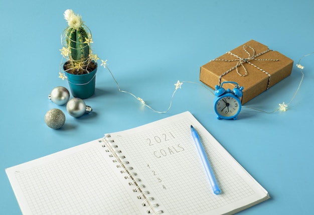 Photo new year goals written in notebook with christmas gift box andcactus decorated with christmas lights