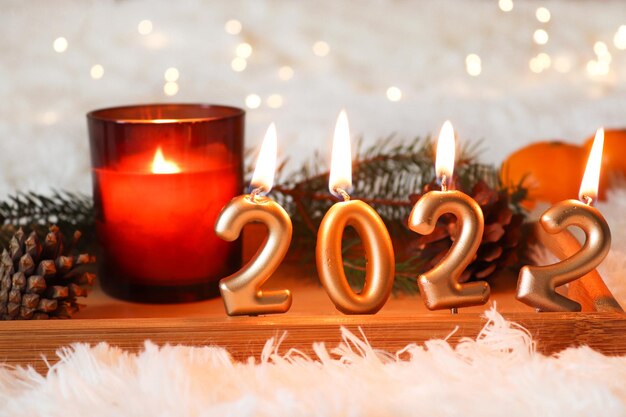 New Year greeting card Cozy home winter composition with candlesnumbers 2022 on wooden tray