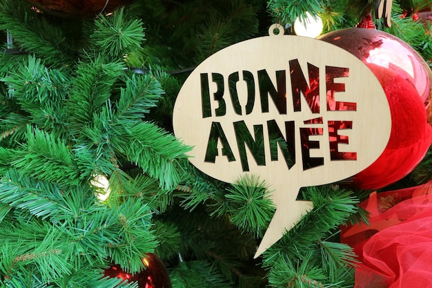 Foto ornamento di auguri di capodanno in francese che significa buon anno sull'albero di natale